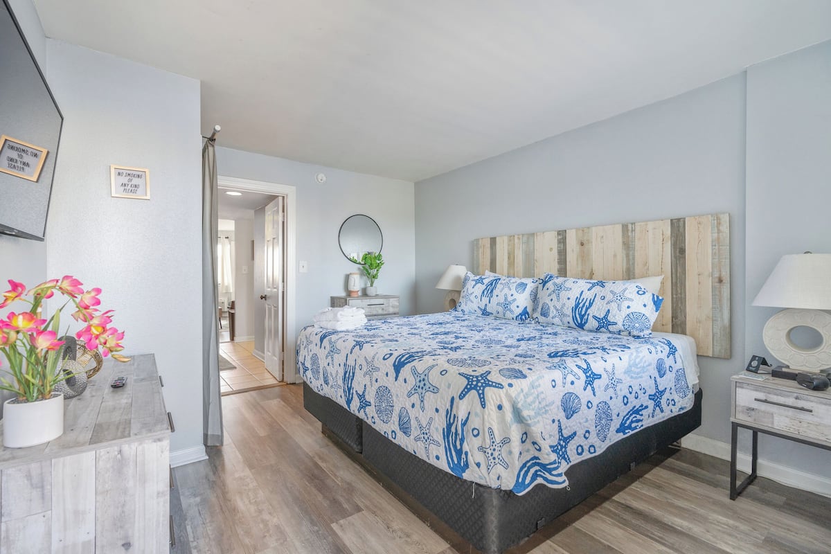 Une chambre à coucher avec un lit, des tables de chevet, une commode, un miroir et une plante en pot.