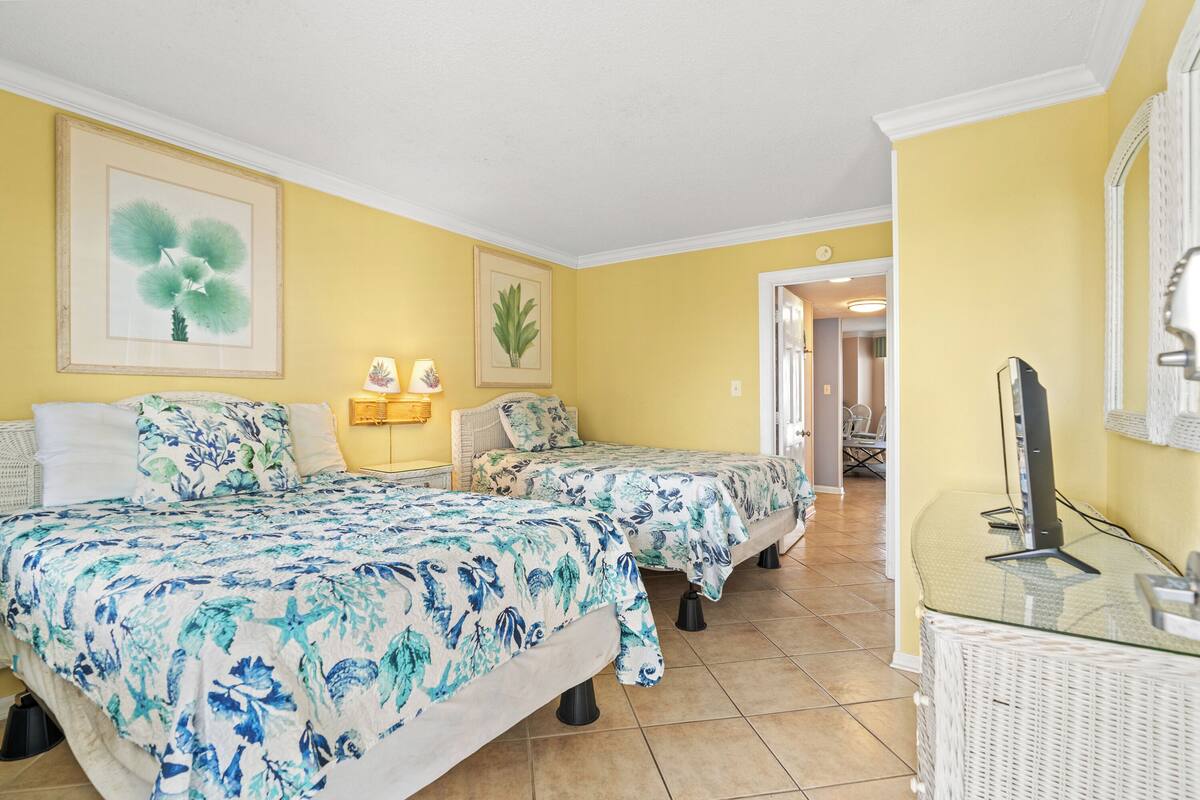 Une chambre avec deux lits, un bureau avec un ordinateur et une chaise.