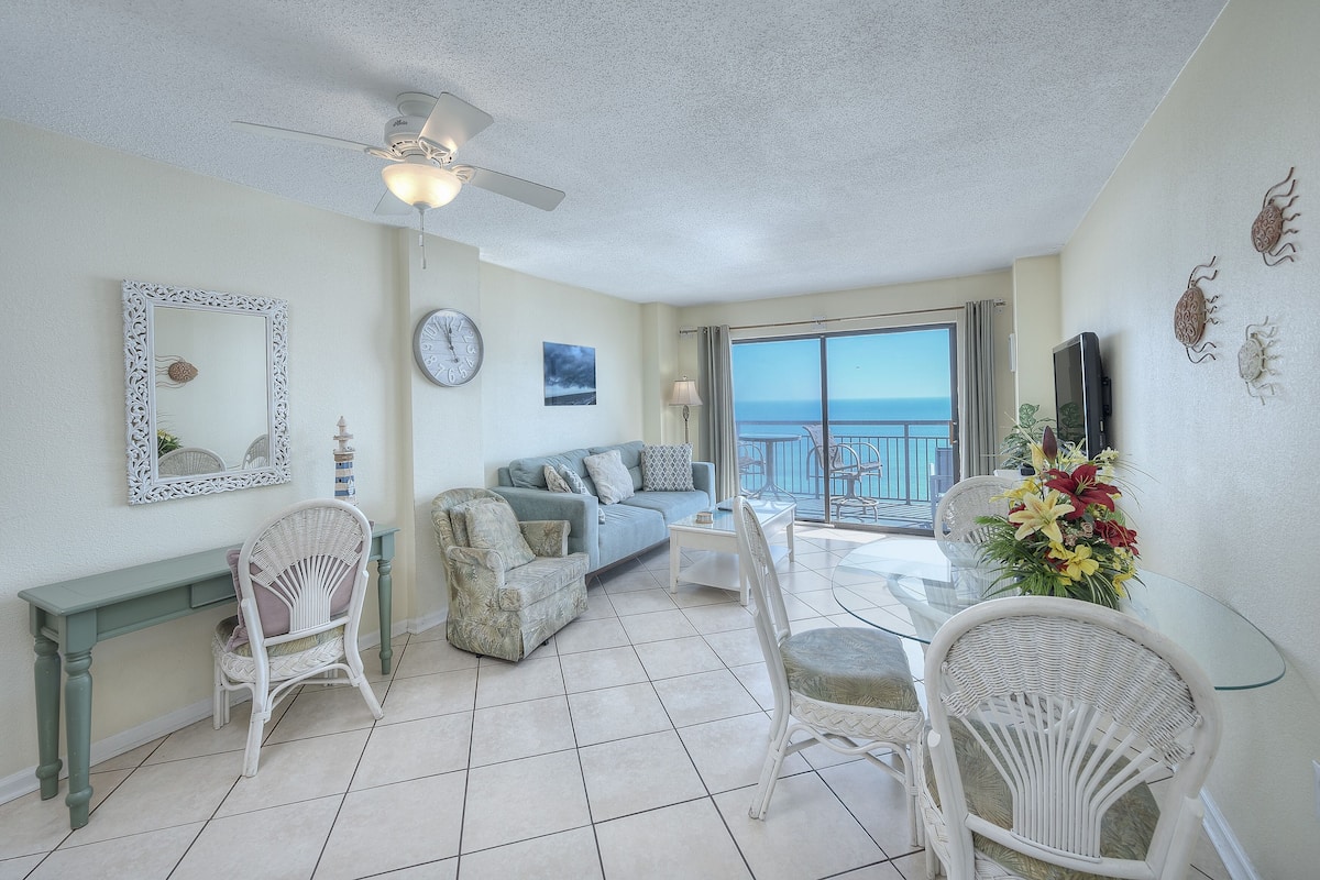 Un salon comprenant un canapé, des fauteuils, une table basse, un téléviseur et un balcon avec vue.