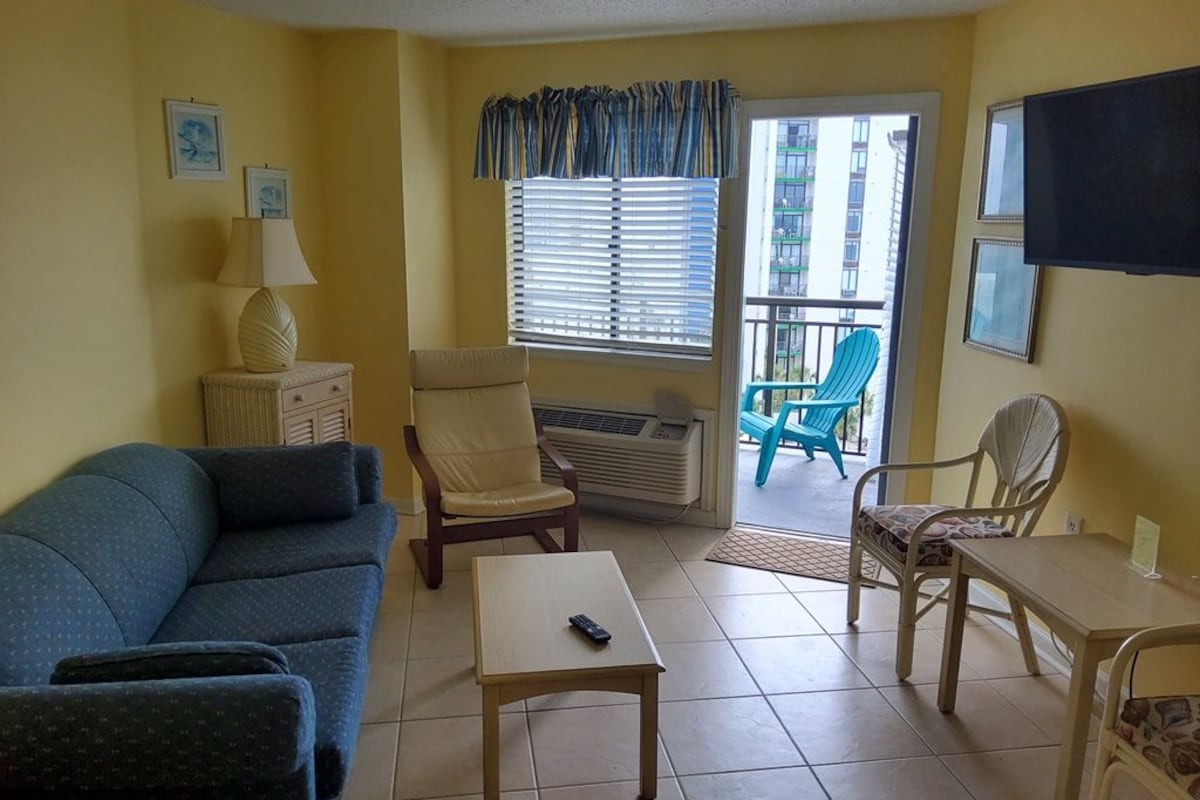 Un salon avec un canapé, des fauteuils, une petite table et un téléviseur.