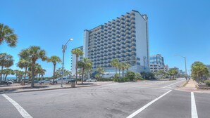 Un hotel moderno con una estructura de rascacielos, una zona de estacionamiento y palmeras a lo largo de la calle.
