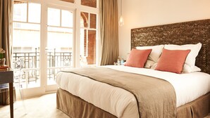 A hotel room with a large bed, a view through a glass door to an outdoor balcony, and a decorative headboard. - The Bull and The Hide (London)