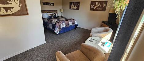 A hotel room with a bed, a chair, a desk, and a TV.
