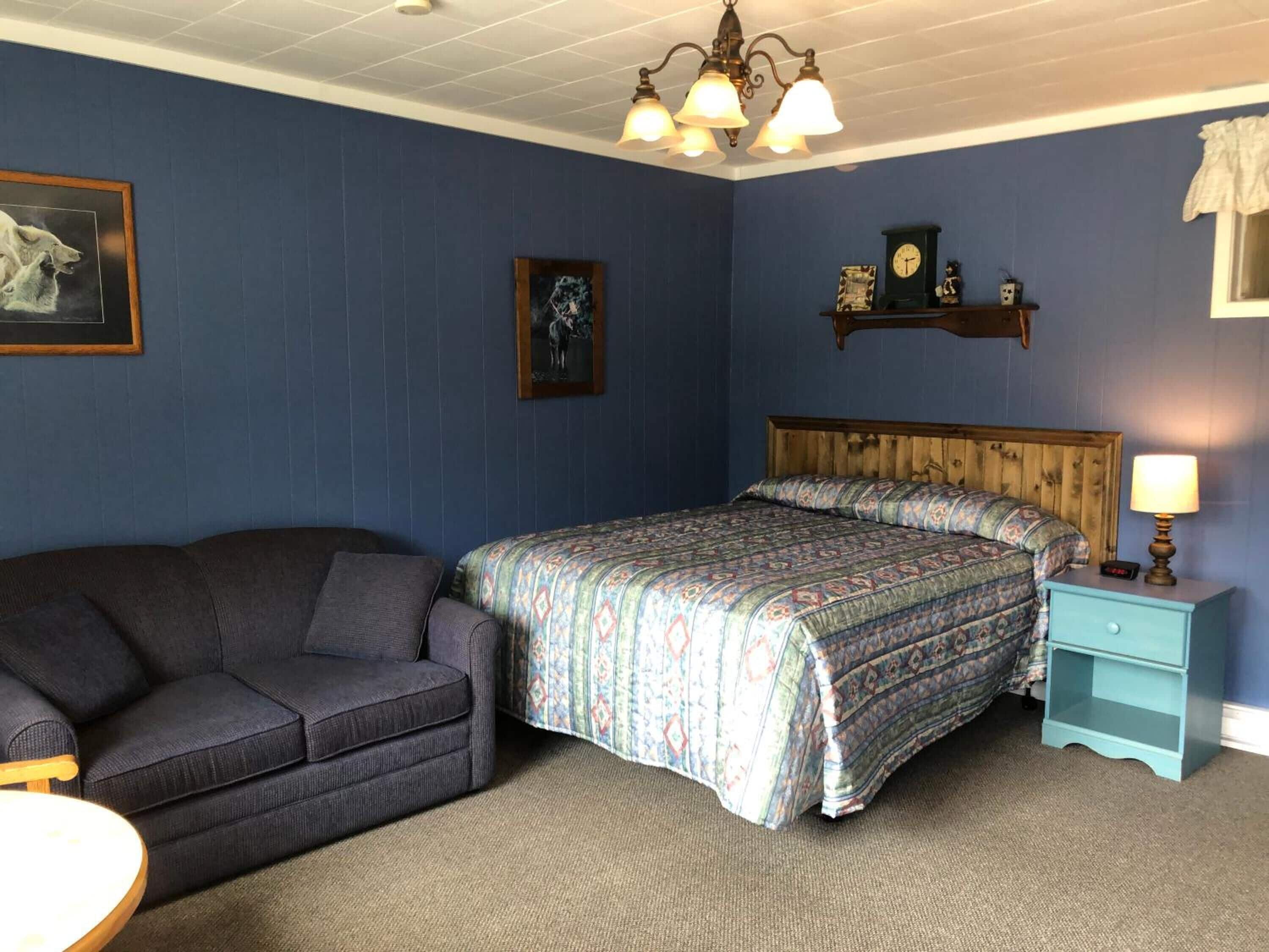 Ein Schlafzimmer mit Bett, Couch, Nachttisch und Wanduhr.