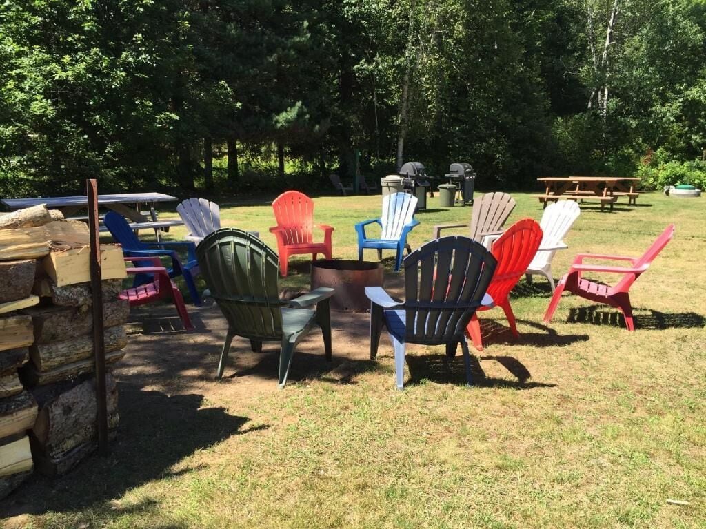 An outdoor seating area with Adirondack chairs and picnic tables.
