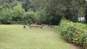 A grassy outdoor area with a stone fire pit surrounded by benches. - Valley Inn (Hamilton)