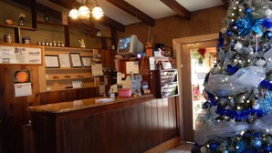 A reception area with a wooden counter, a television, and a Christmas tree. - Valley Inn (Hamilton)