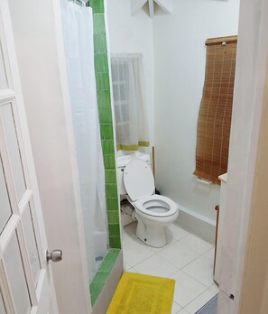 Ein Badezimmer mit Toilette, Duschvorhang und einer gelben Matte.