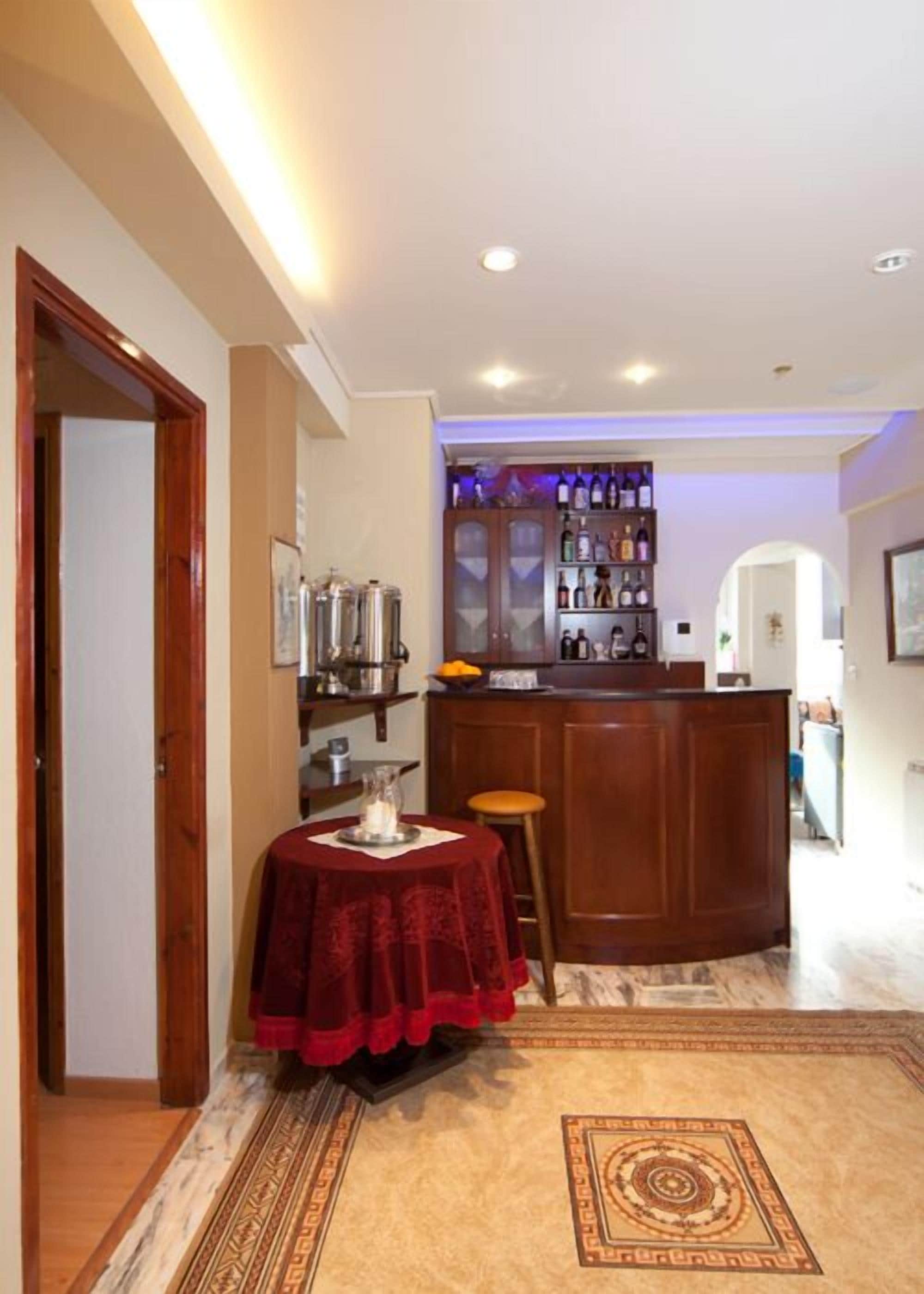 A bar area with a wooden counter and shelves of bottles.