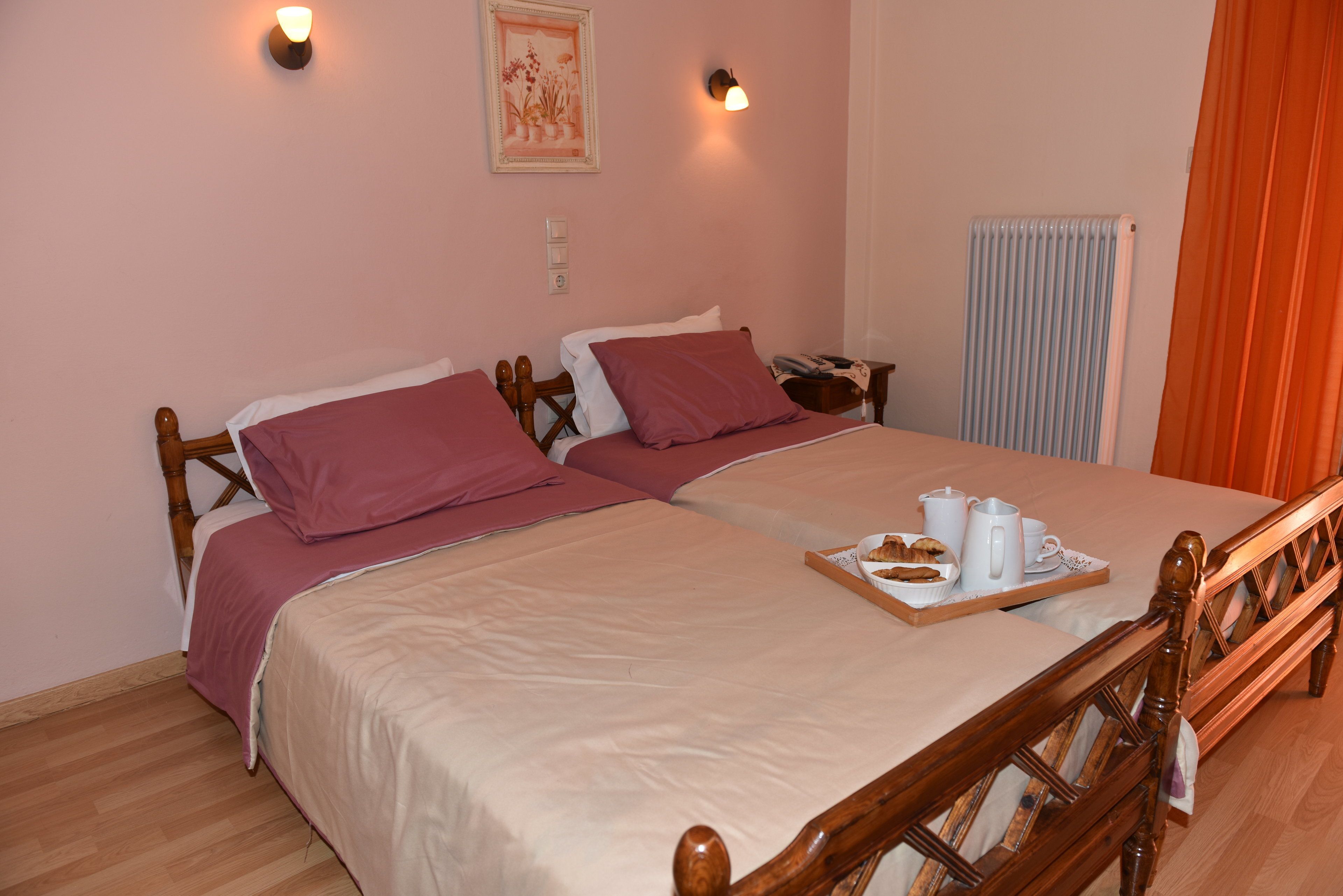 A double bed with a tray of breakfast items, a bedside table with a lamp, and a radiator.