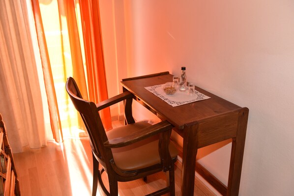 A wooden dining table with a lace doily, a glass bowl, and a bottle. - 40 Platania Hotel (Istiaia-Aidipsos)