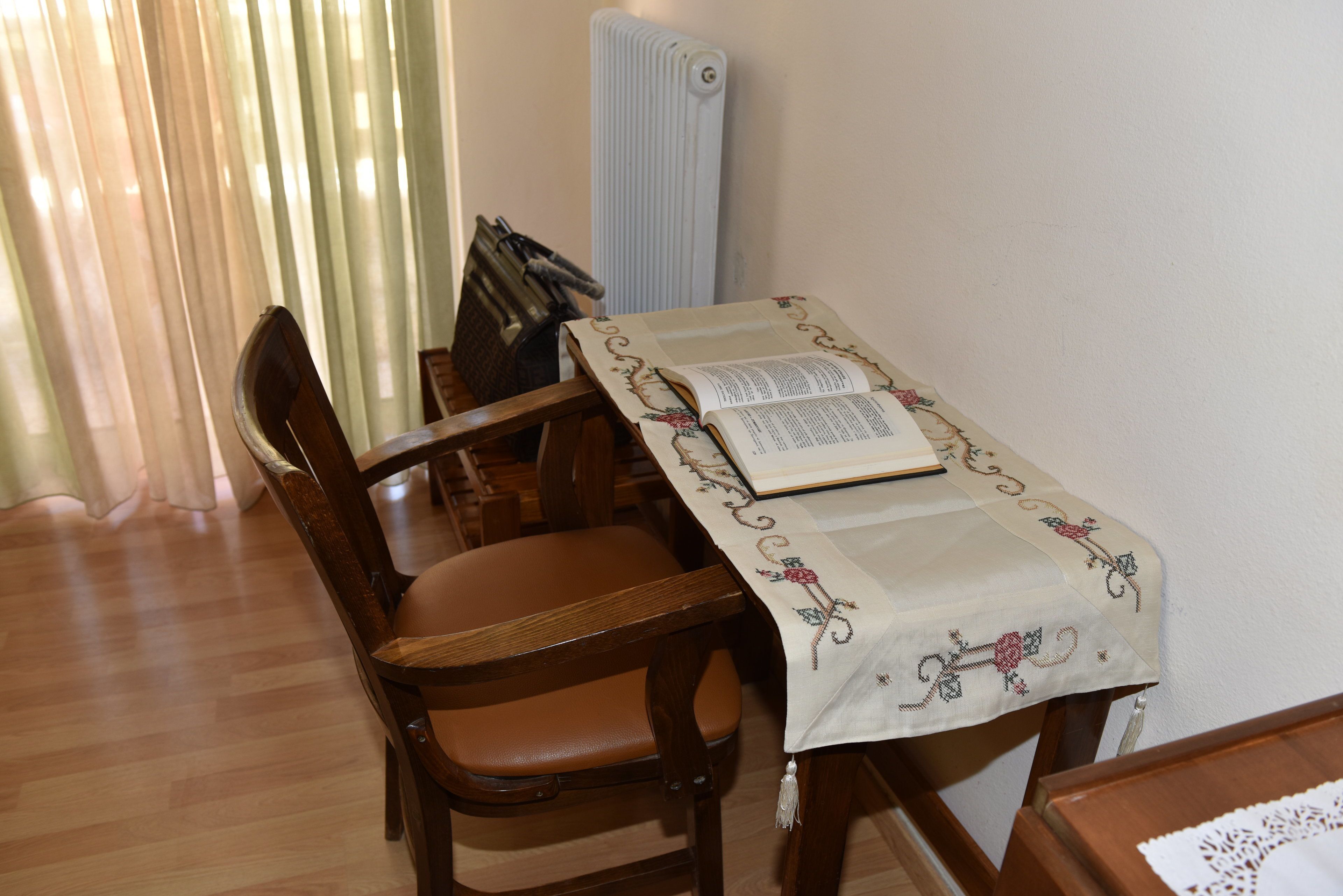 A dining area with a table covered by a tablecloth, a chair, and a book.