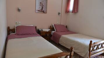 Una camera da letto con due letti singoli, ciascuno con struttura in legno e biancheria rosa. C'è un comodino con un telefono e una lampada tra i letti. Un quadro è appeso al muro sopra i letti.