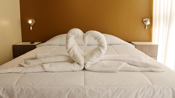 Ein Hotelzimmer mit Bett, Nachttisch und Wandlampe.