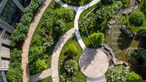 An aerial view of a landscaped urban area with curved pathways, a central circular plaza, and surrounding greenery. - Xiandai Gloria Grand Hotel Changsha (Changsha)
