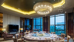A spacious dining area with a round table, surrounded by chairs, and a large chandelier. - Xiandai Gloria Grand Hotel Changsha (Changsha)