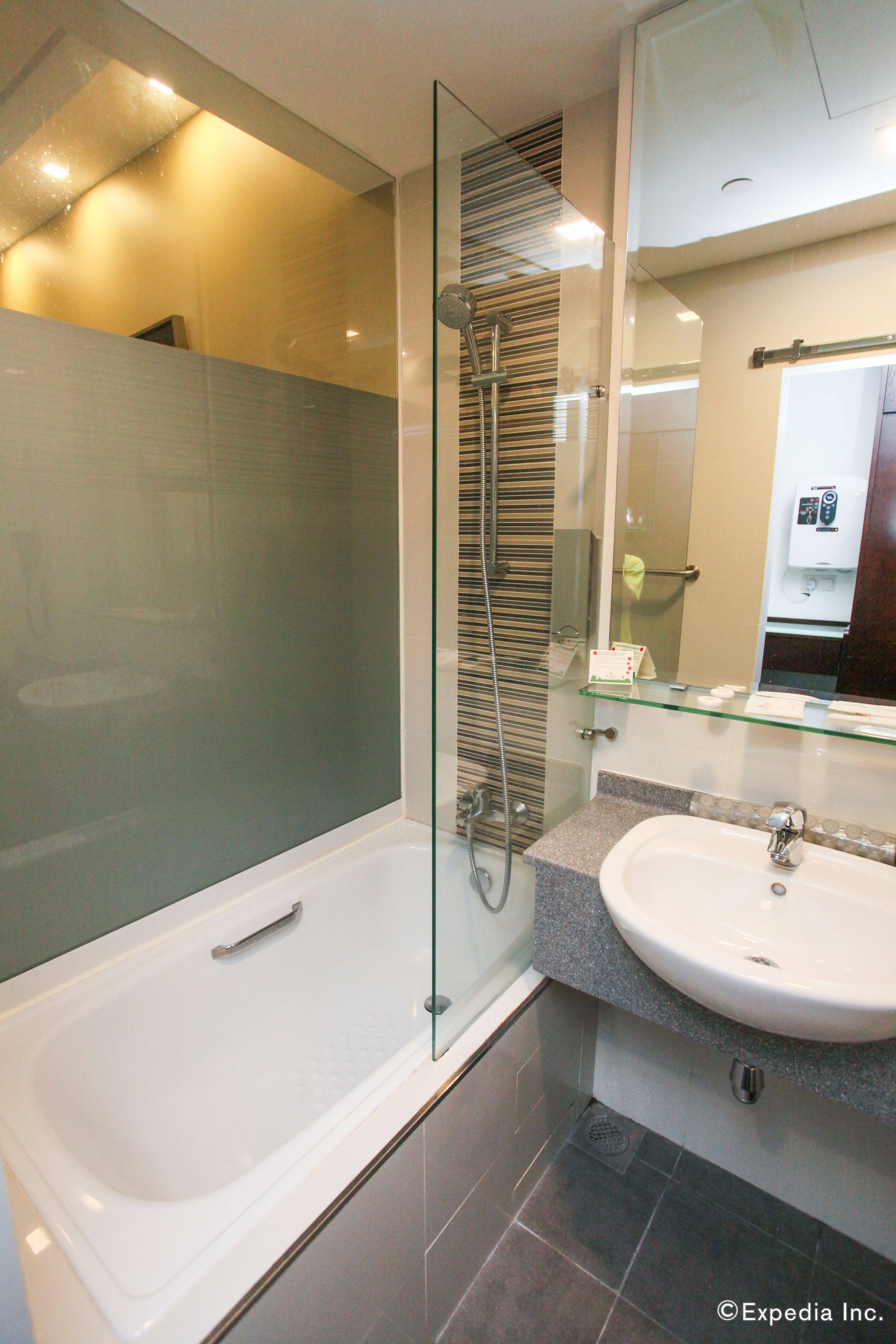 Un baño moderno con ducha envuelta en cristal, una bañera blanca y una encimera de granito con lavamanos.