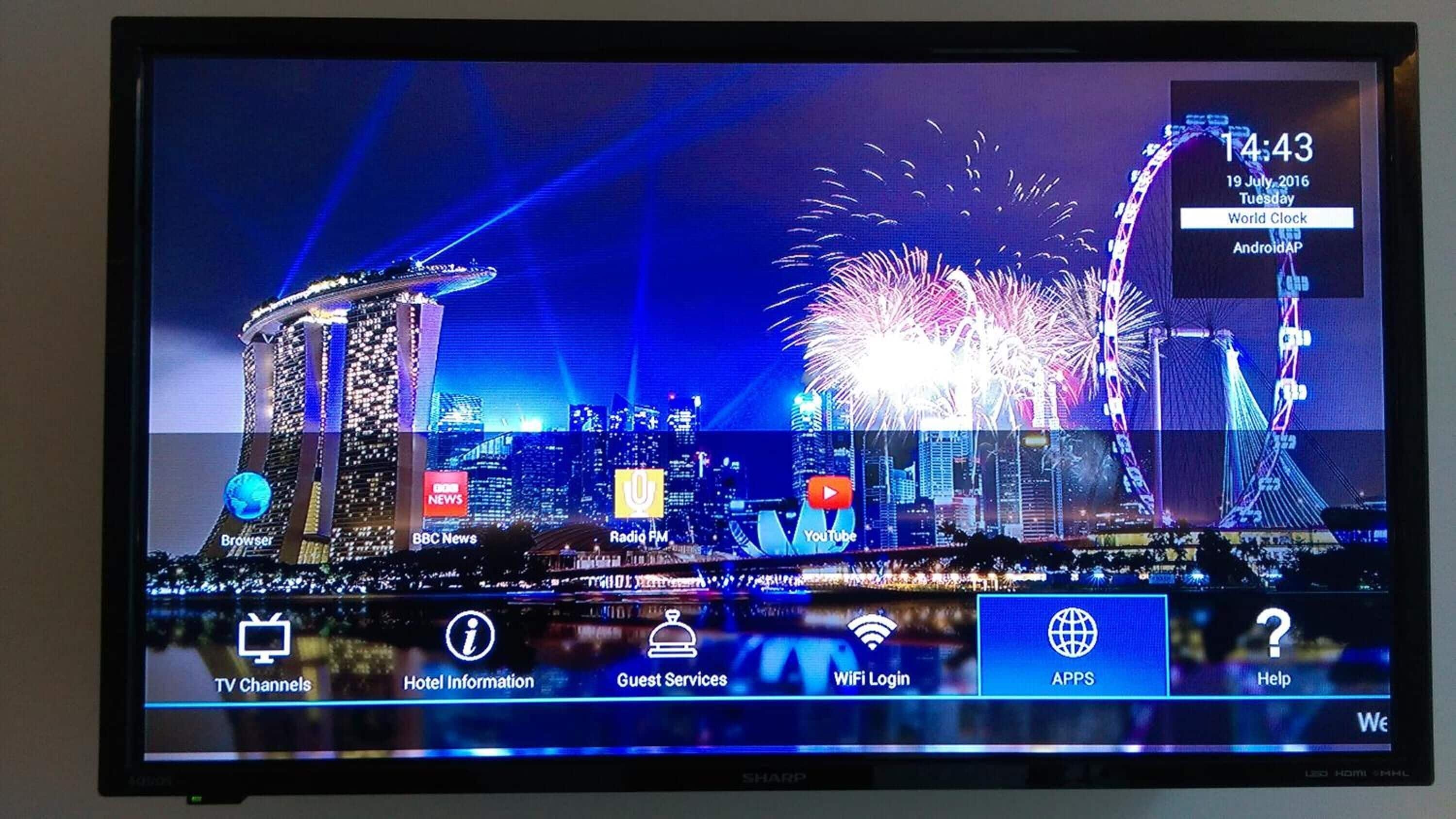 A hotel room with a cityscape view, including a prominent tower and fireworks display.