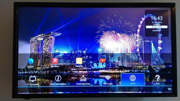 A hotel room with a cityscape view, including a prominent tower and fireworks display.
