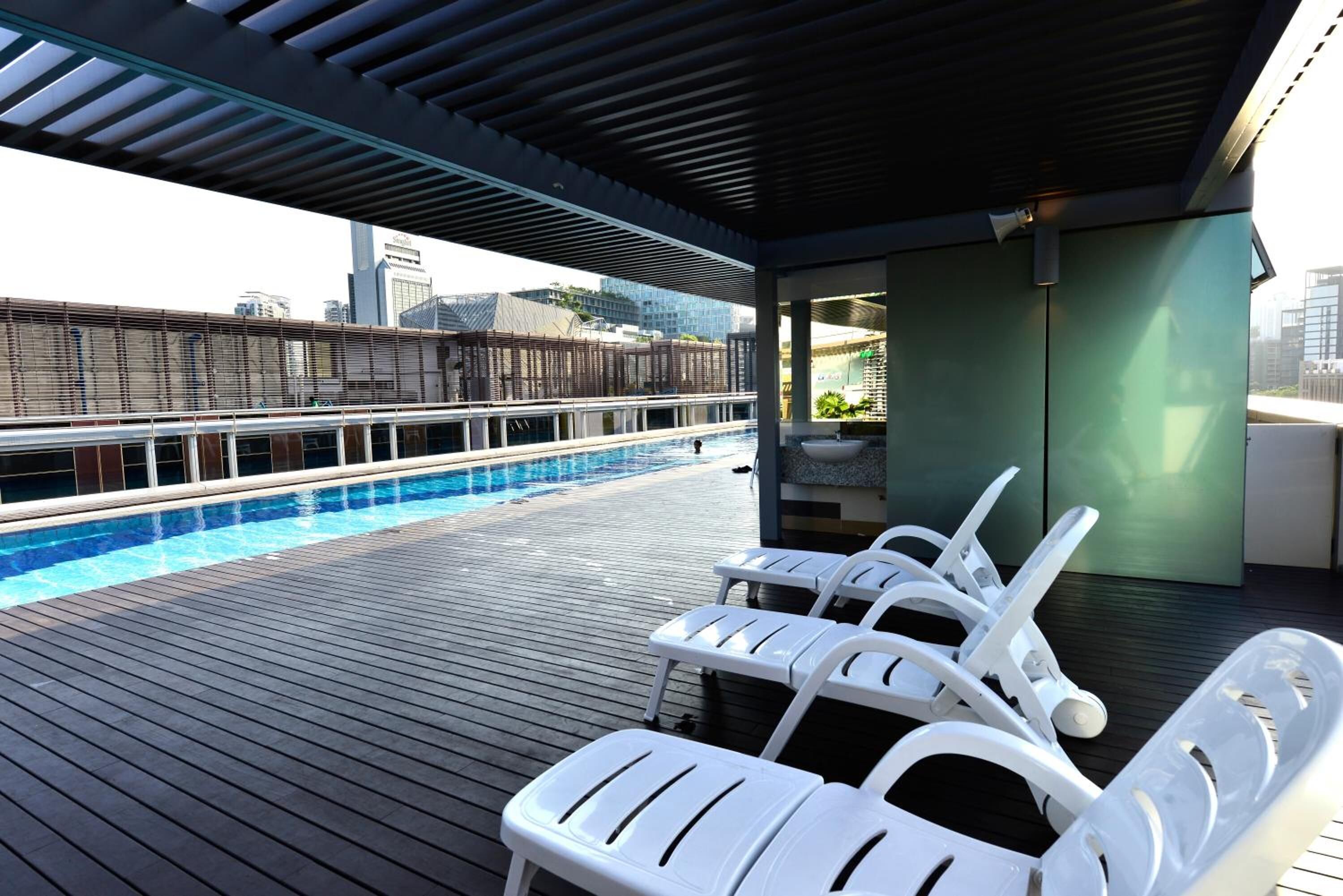 A rooftop pool area with white lounge chairs and a view of the city skyline.