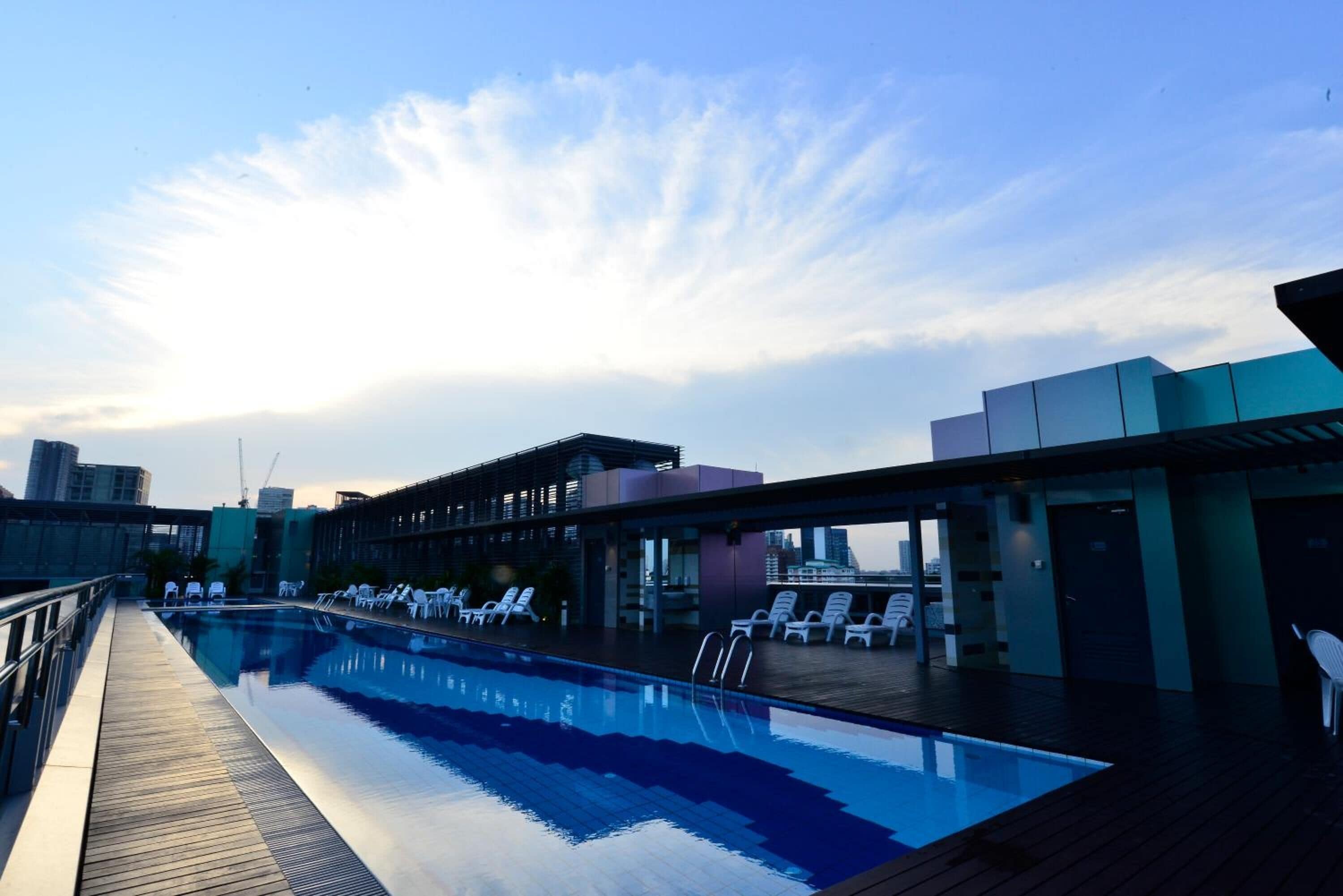A rooftop pool with lounge chairs and a wooden deck.