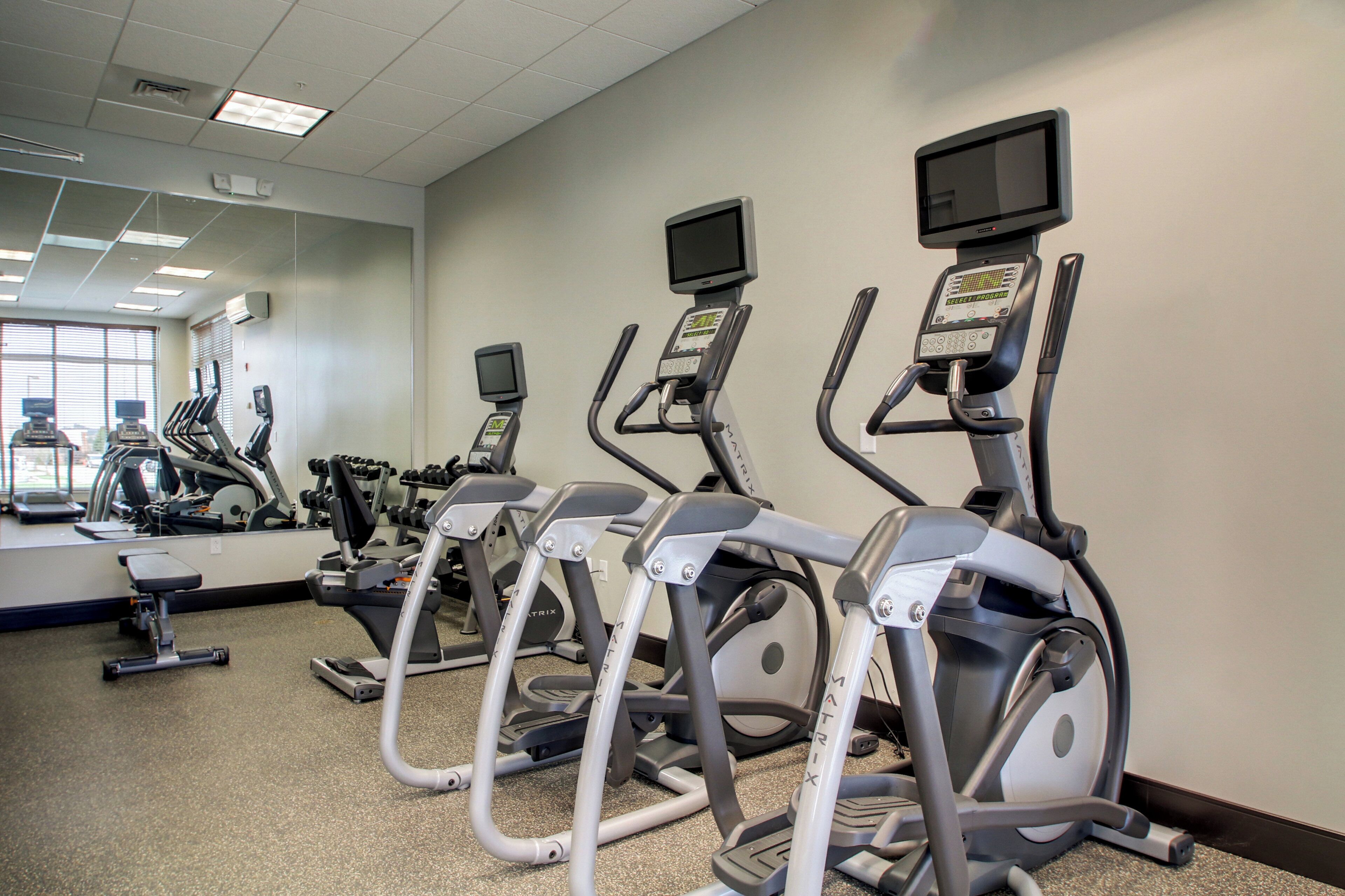 A gym with treadmills, stationary bikes, and a mirrored wall.
