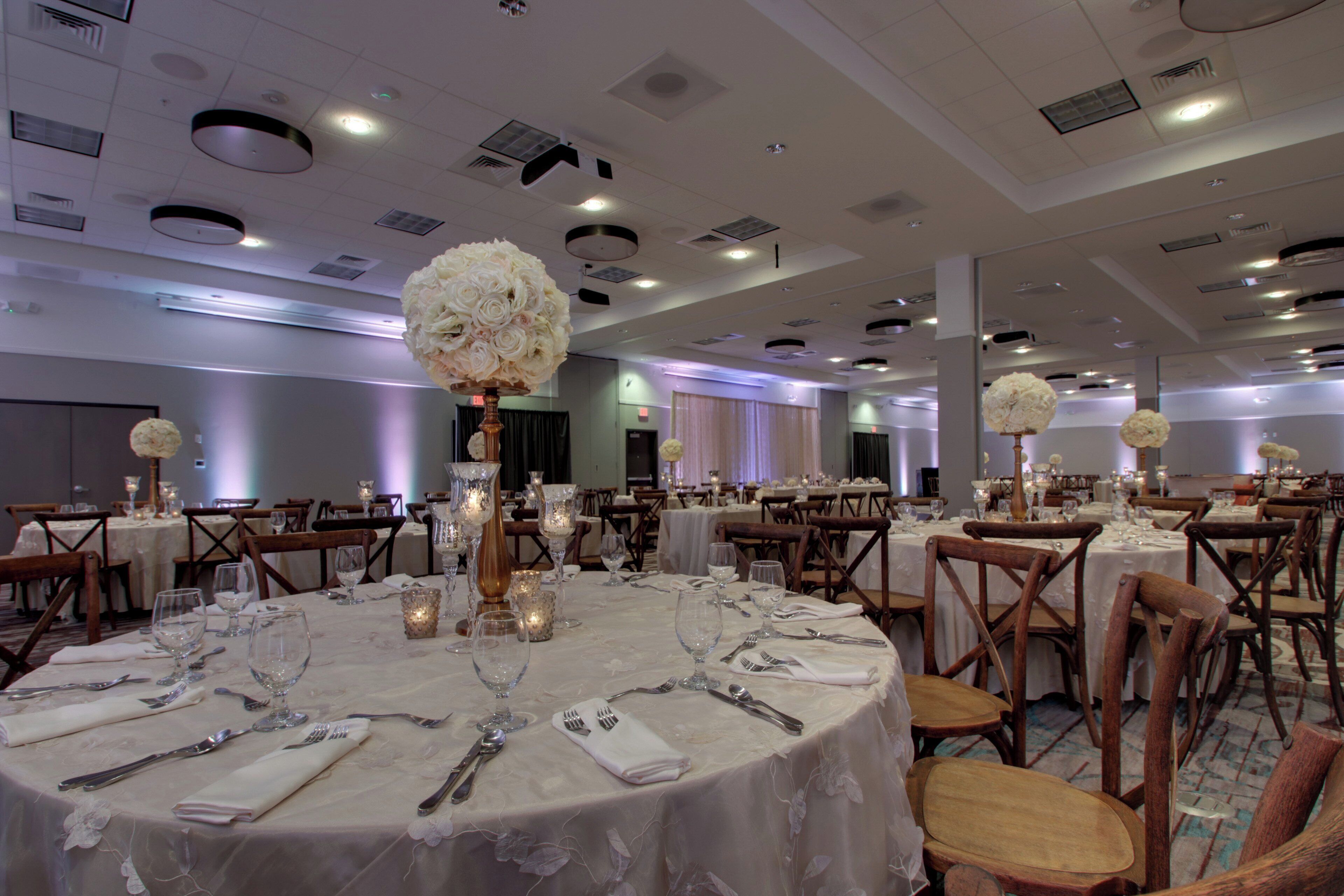 A banquet hall with round tables set for dining, featuring white tablecloths and floral centerpieces.