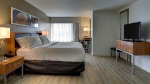 A modern hotel room with a large bed, a desk with a computer, a television, and a desk lamp. - Holiday Inn & Suites Peoria At Grand Prairie by IHG (Peoria)