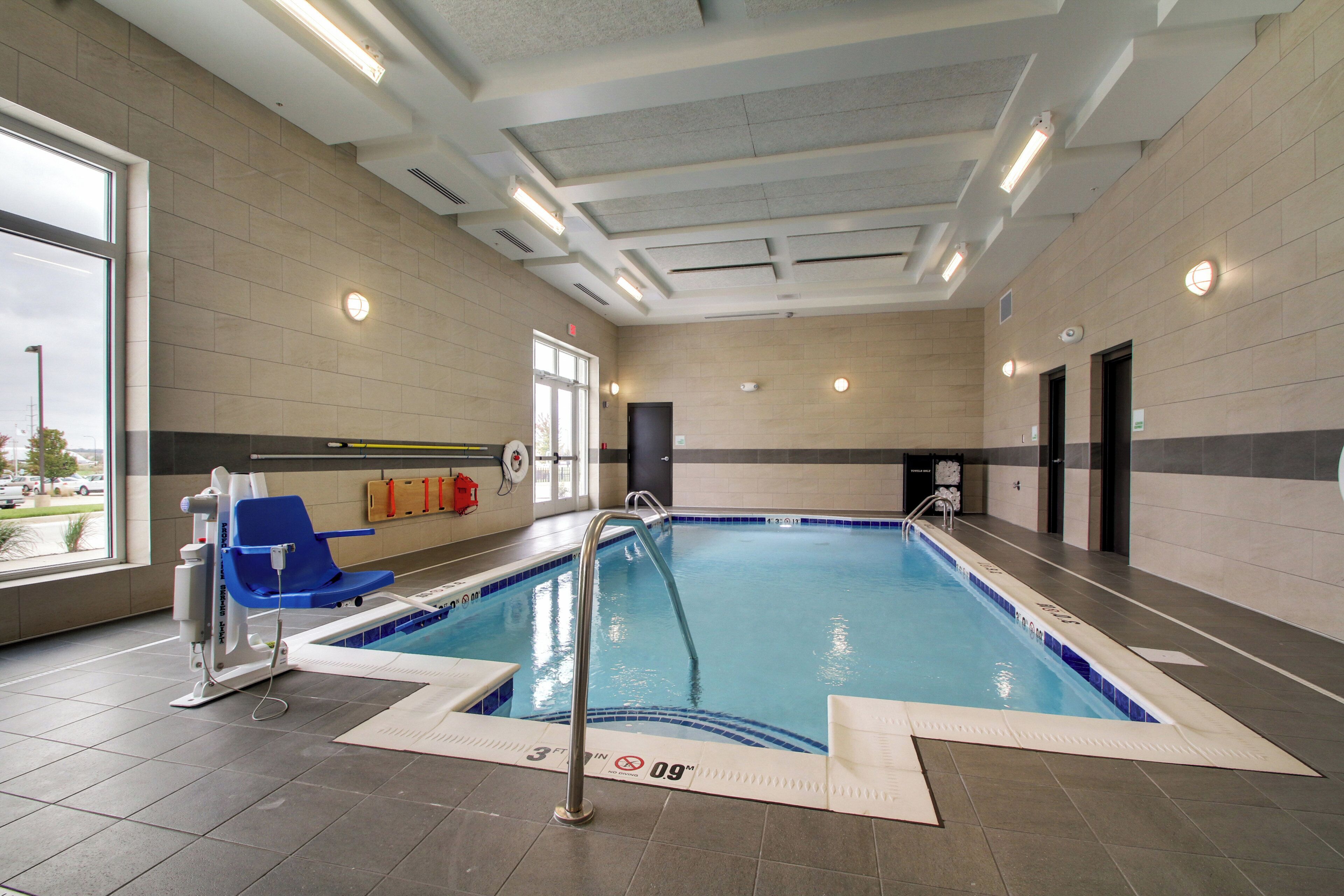 An indoor swimming pool with a lifeguard chair, safety equipment, and clear poolside markings.