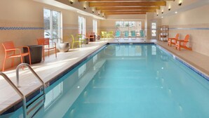 A swimming pool with a wooden ceiling, tiled walls, and colorful chairs. - Home2 Suites by Hilton Fort Smith AR (Fort Smith)