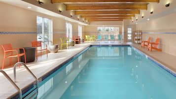A swimming pool with a wooden ceiling, tiled walls, and colorful chairs.