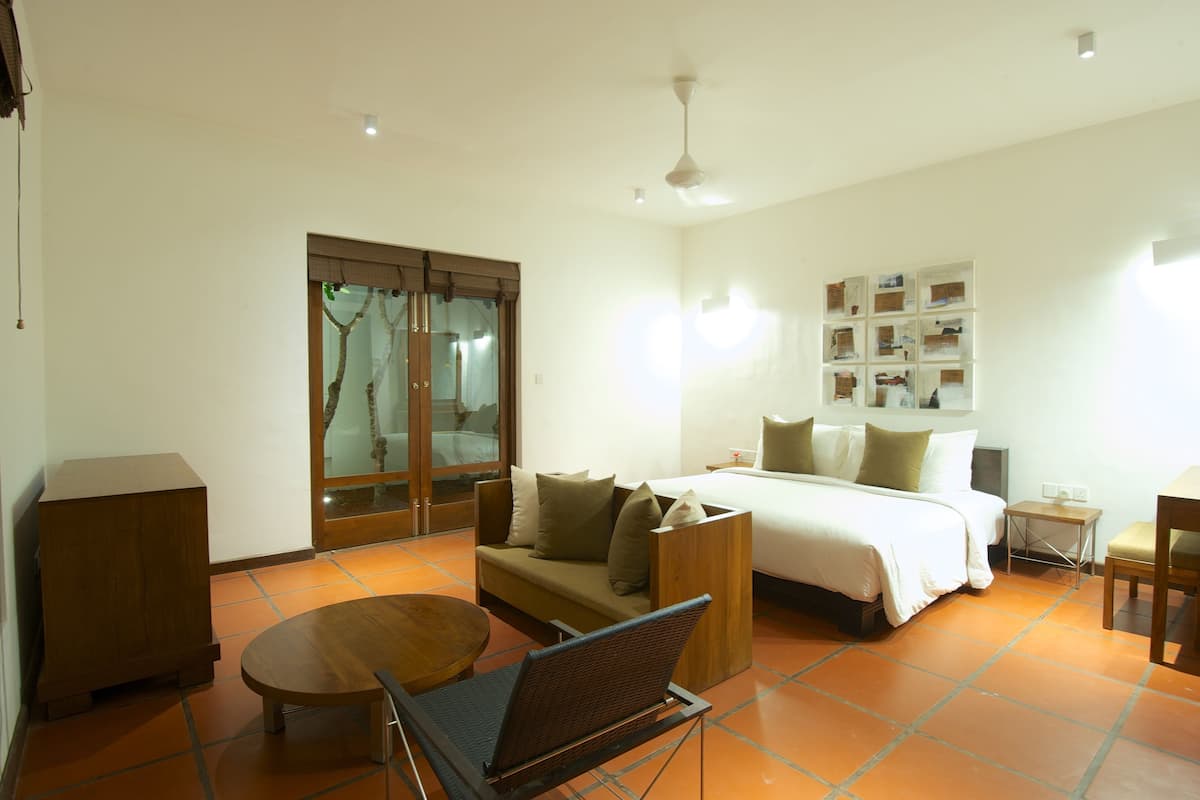 A hotel room with a bed, sofa, dining table, and a small side table.