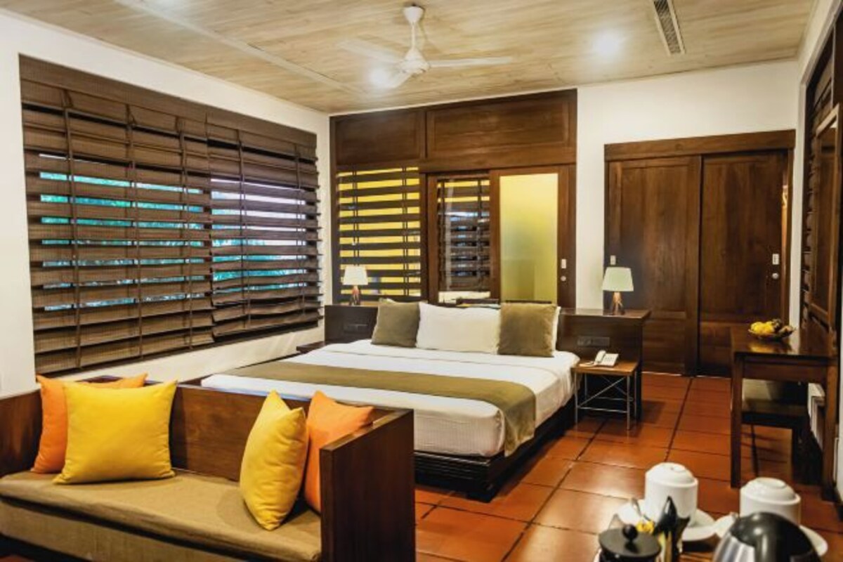 Una habitación de hotel con cama, sofá, escritorio y ventana con persianas.