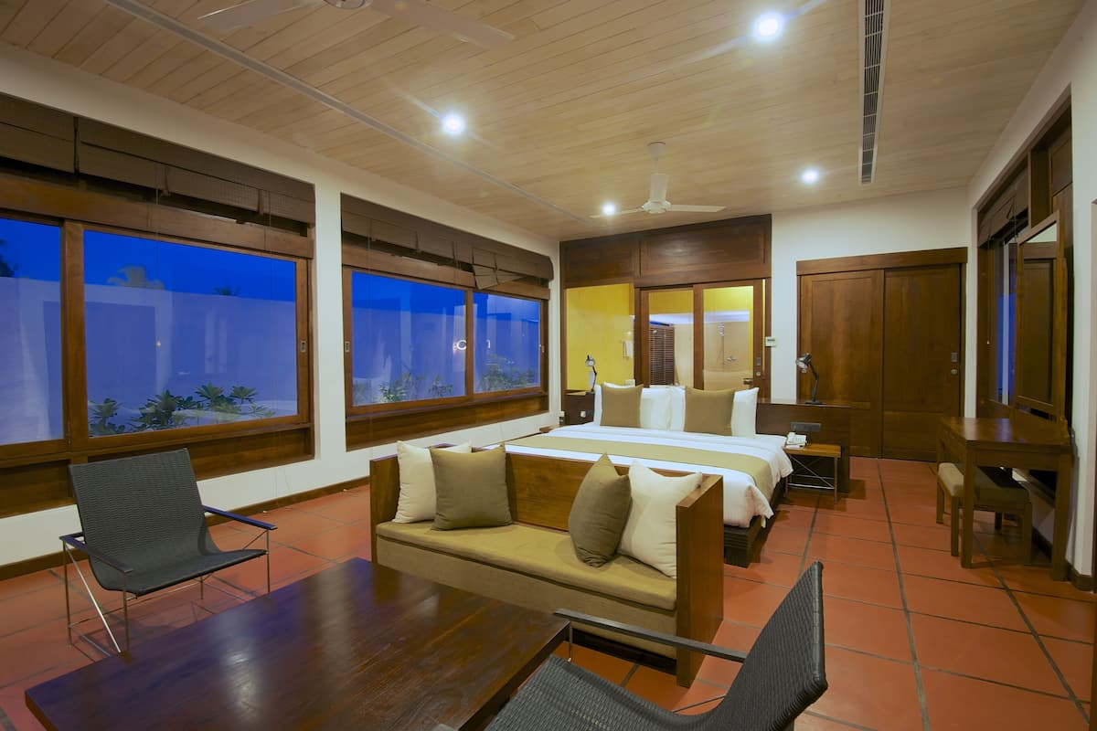 A hotel room with a bed, sofa, and a dining table.