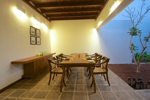 A dining area with a long wooden table set for six, surrounded by chairs. - Jetwing Thalahena Villa (Negombo)