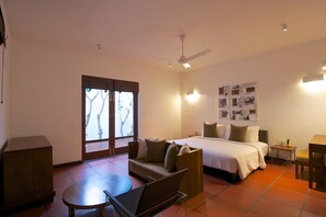 A hotel room with a bed, a sofa, a dining table, and a ceiling fan. - Jetwing Thalahena Villa (Negombo)