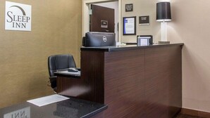 A hotel reception desk with a computer, a chair, and a sign for Sleep Inn. - Sleep Inn Coney Island (Brooklyn)