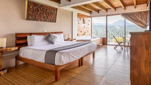 Un'ampia camera da letto con un letto grande, travi in legno, un balcone con vista e un design rustico delle pareti.