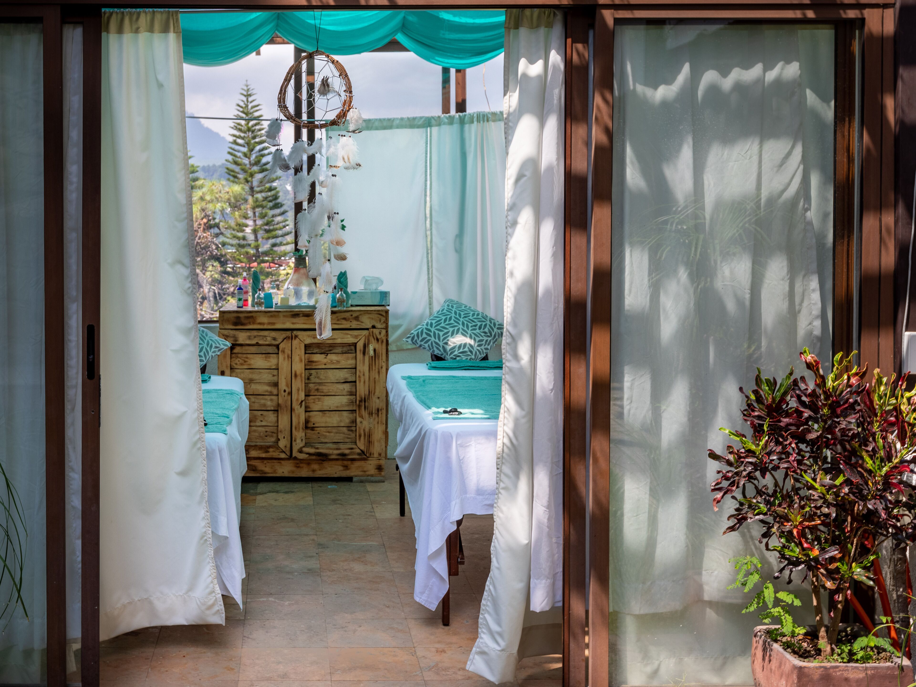A room with two beds, a wooden dresser, and a dreamcatcher hanging above.