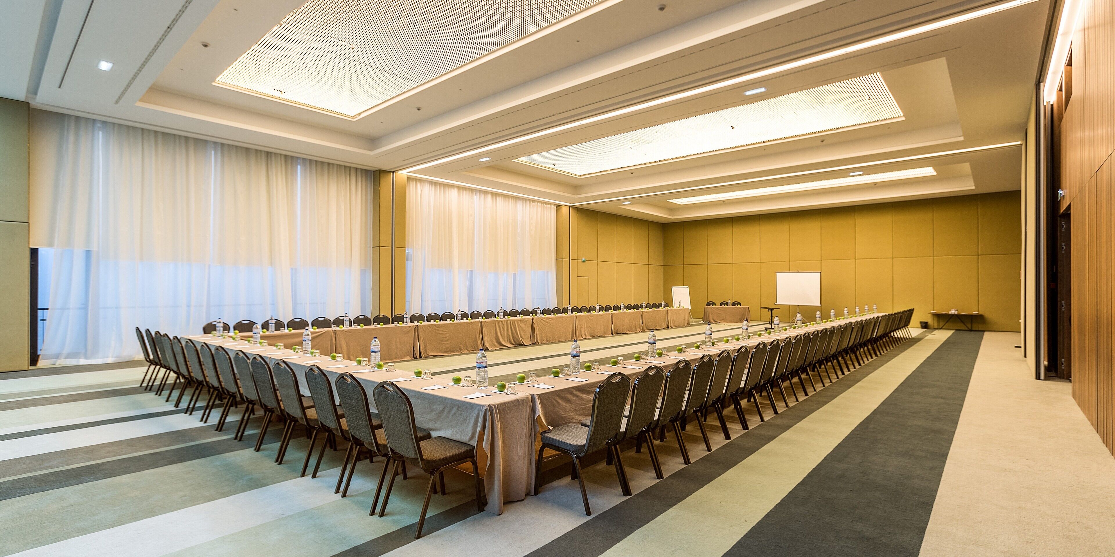 A conference room with a long table, chairs, and a projector screen.