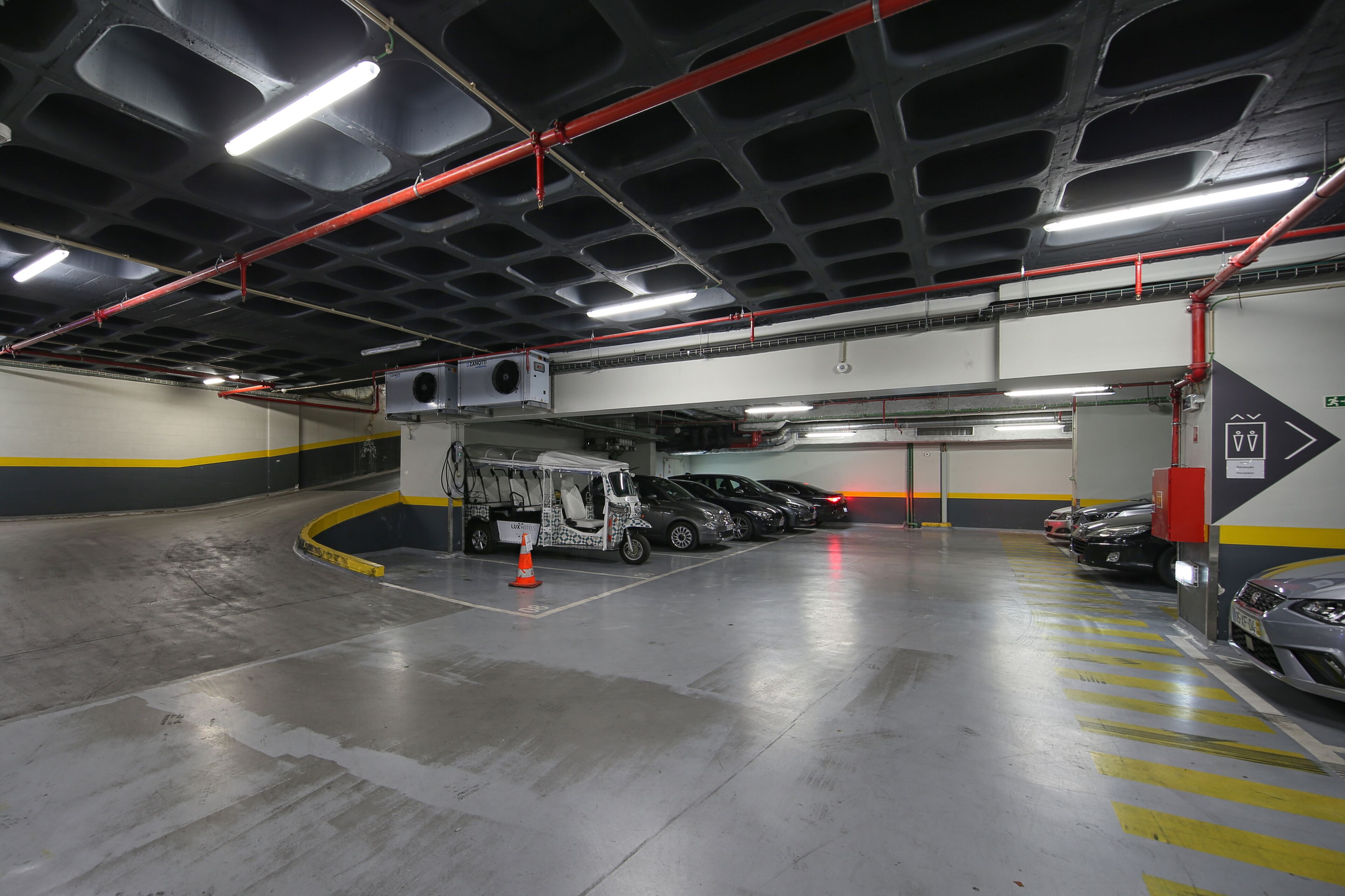 A multi-level parking garage with several cars parked, a service vehicle, and clear signage.