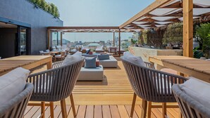 A rooftop terrace with wooden flooring, outdoor seating, and a view of the cityscape. - Lux Lisboa Park (Lisbon)