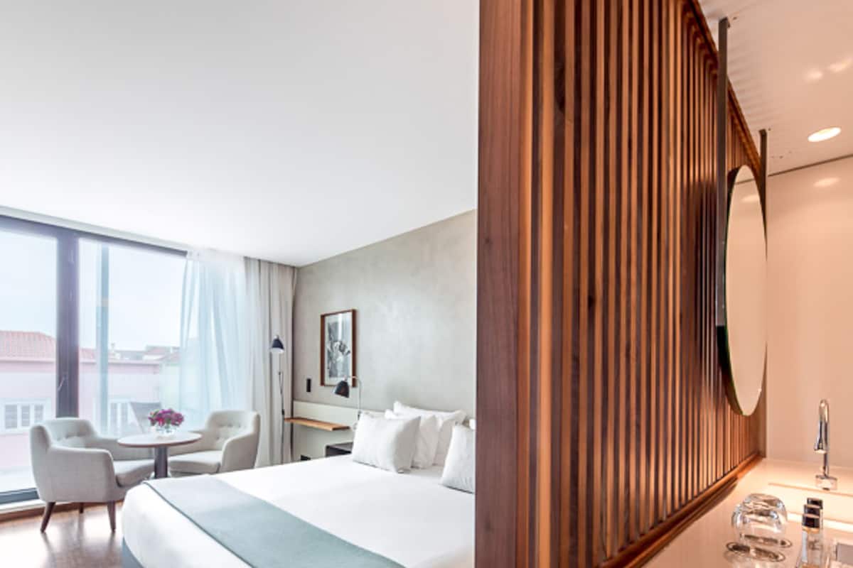 Een moderne hotelkamer met een groot bed, een bureau en uitzicht op de stad.