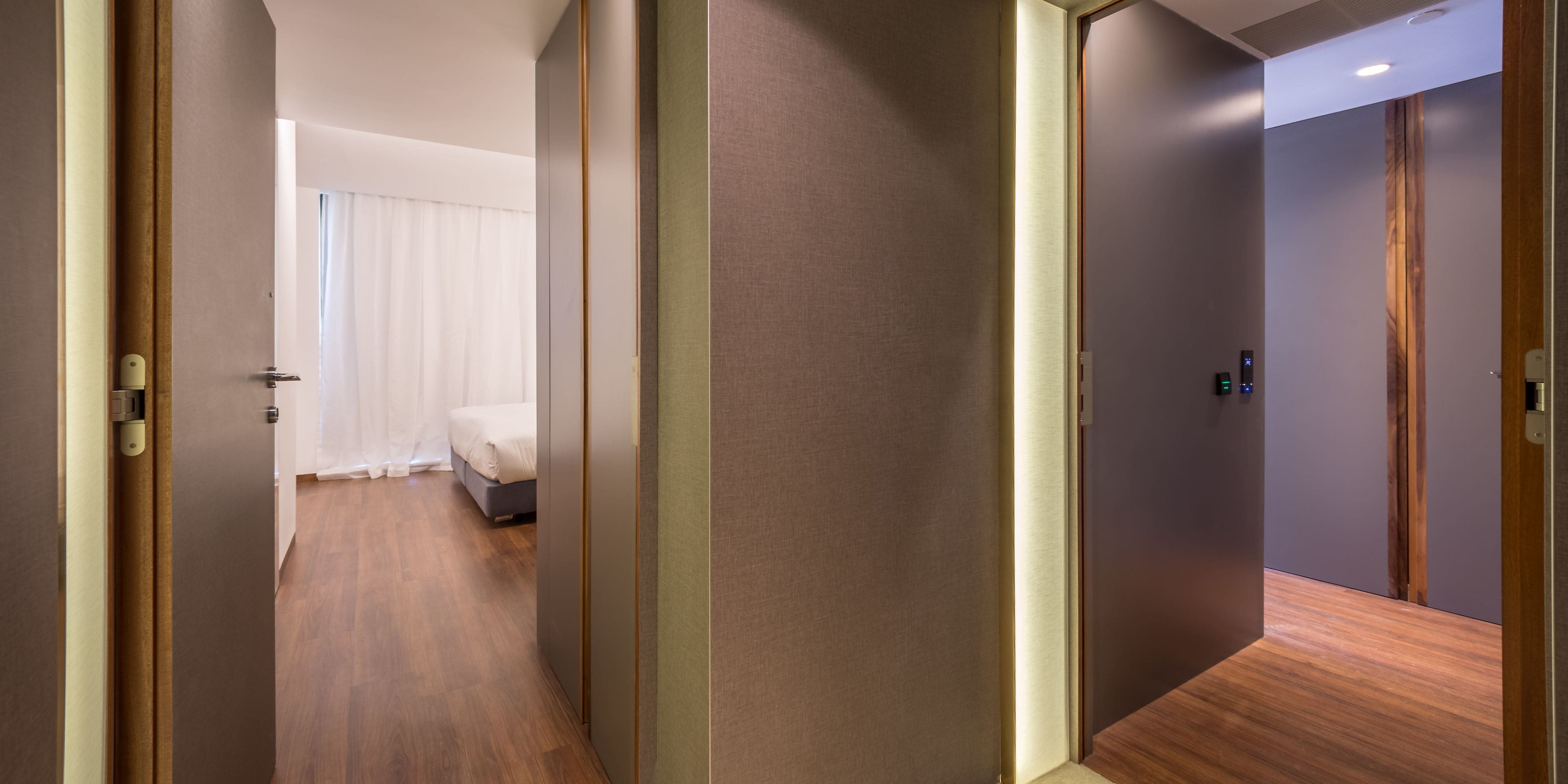 Une chambre d’hôtel avec un lit, un plancher en bois et une porte donnant sur une autre pièce.