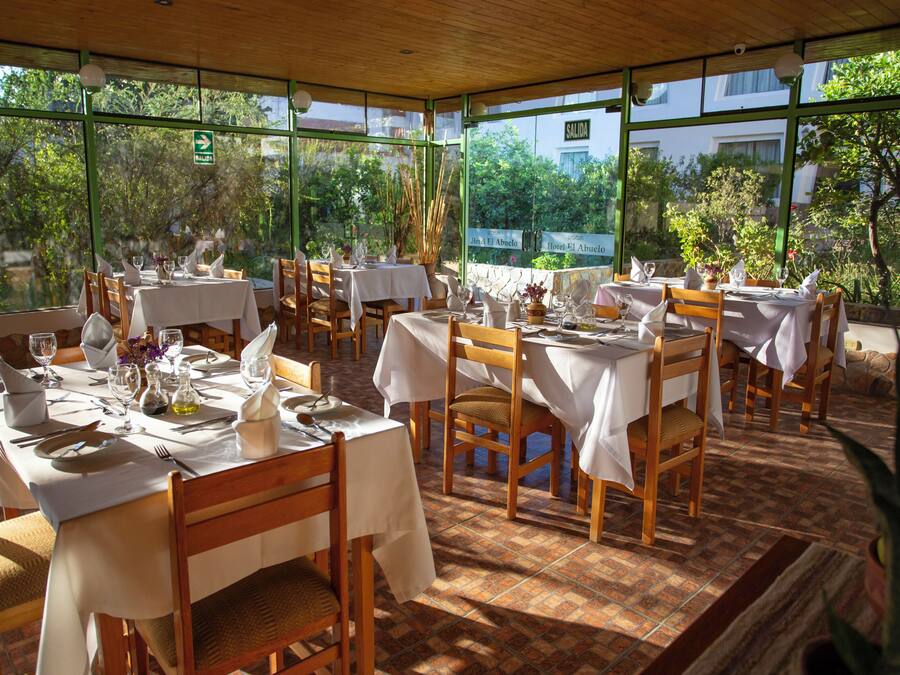 Un restaurante con mesas dispuestas para comer, amplios ventanales y vistas a zonas verdes.