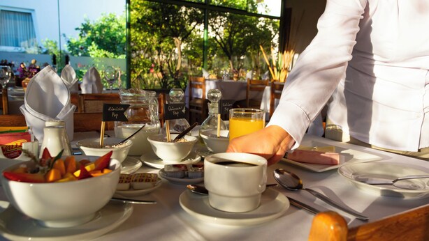 A breakfast setting with various dishes, including a bowl of fruit, a cup of coffee, and a glass of orange juice.