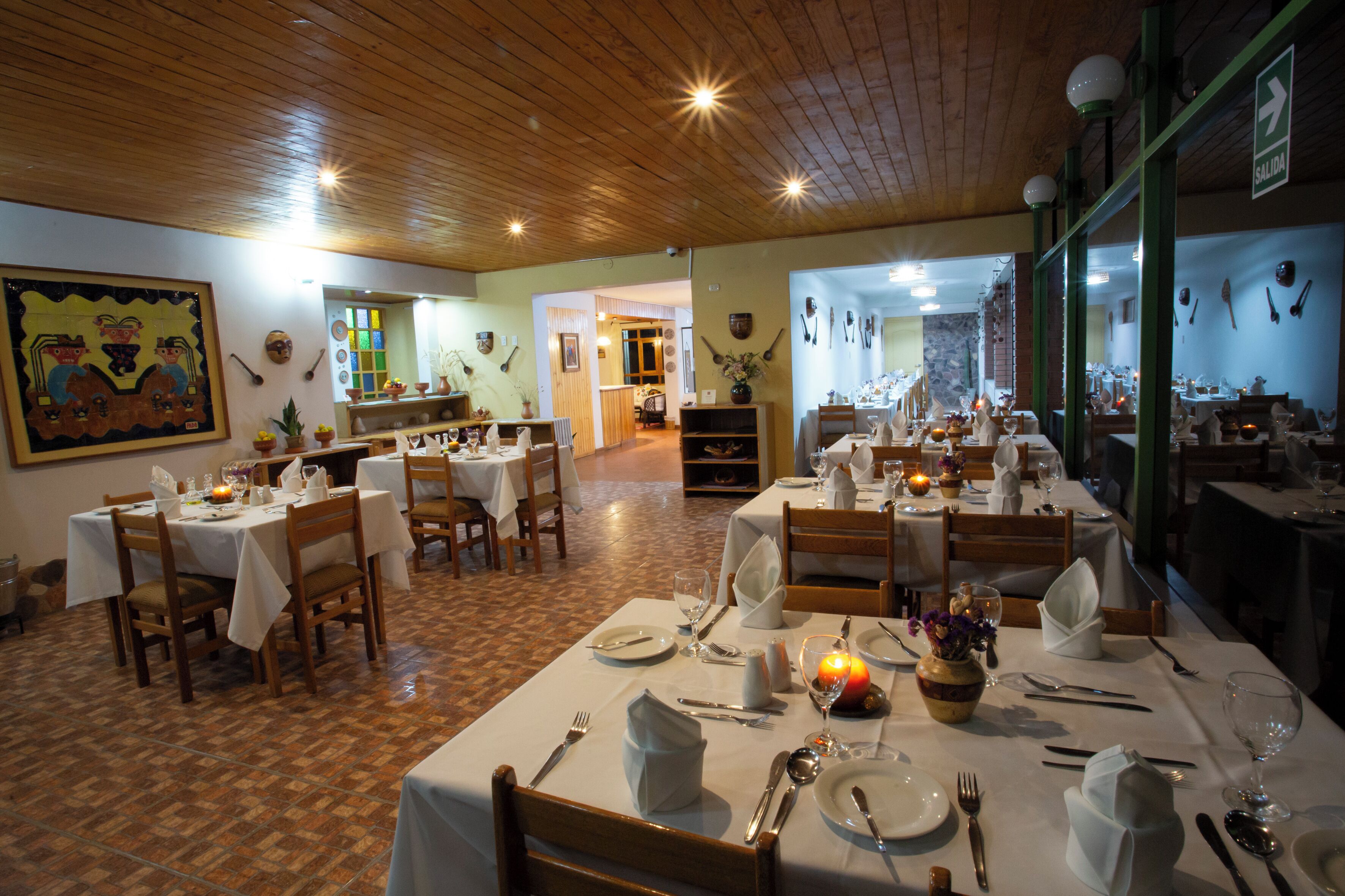 Un restaurante con varias mesas dispuestas para comer, suelo de madera y techo de madera.