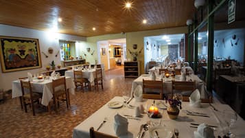 Un restaurante con varias mesas dispuestas para comer, suelo de madera y techo de madera.
