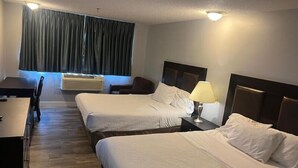 Habitación de hotel con dos camas, un escritorio, una silla y un ventanal con cortinas.