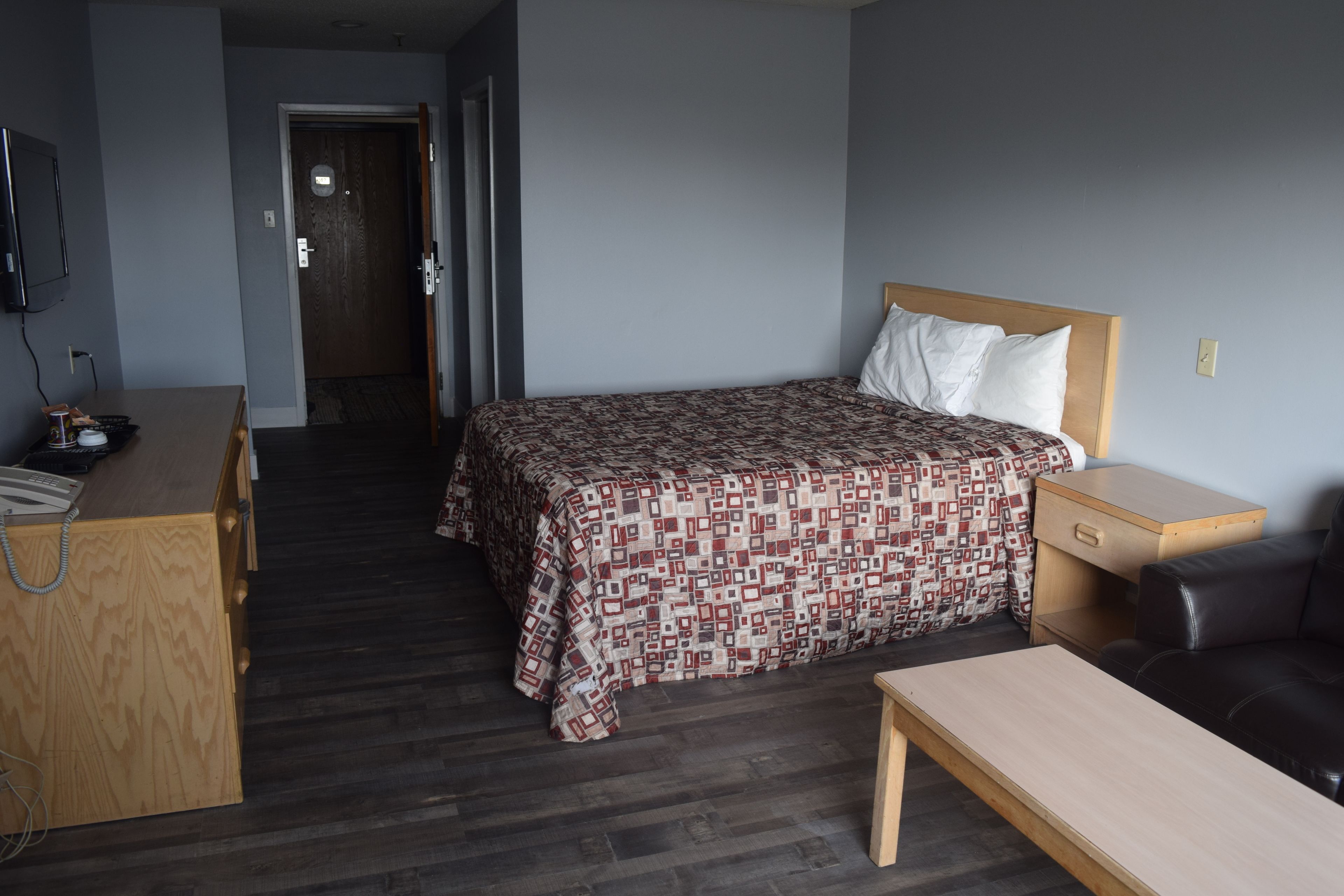 Hotellihuone, jossa on sänky, työpöytä, tuoli ja pieni pöytä.